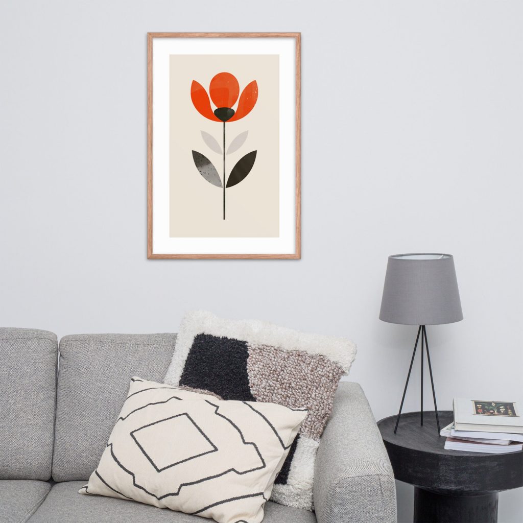 A living room with a gray couch and cushion, a framed minimalistic flower print on the wall, and a side table.