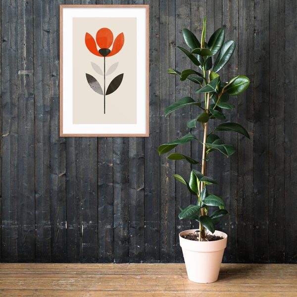 A potted green plant next to a framed flower illustration hanging on a dark wooden wall.