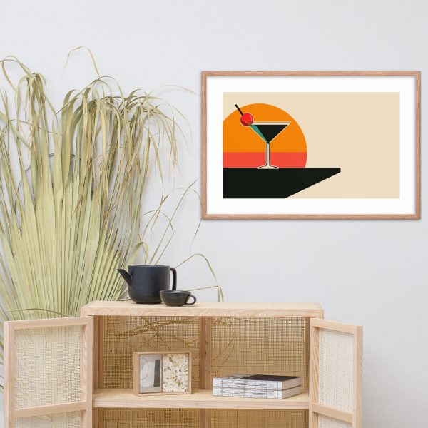 Framed cocktail artwork above wooden cabinet with tea set