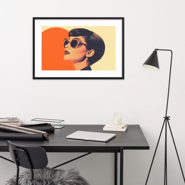 A modern workspace with a stylish table lamp, desk, and wall art of a woman in sunglasses.